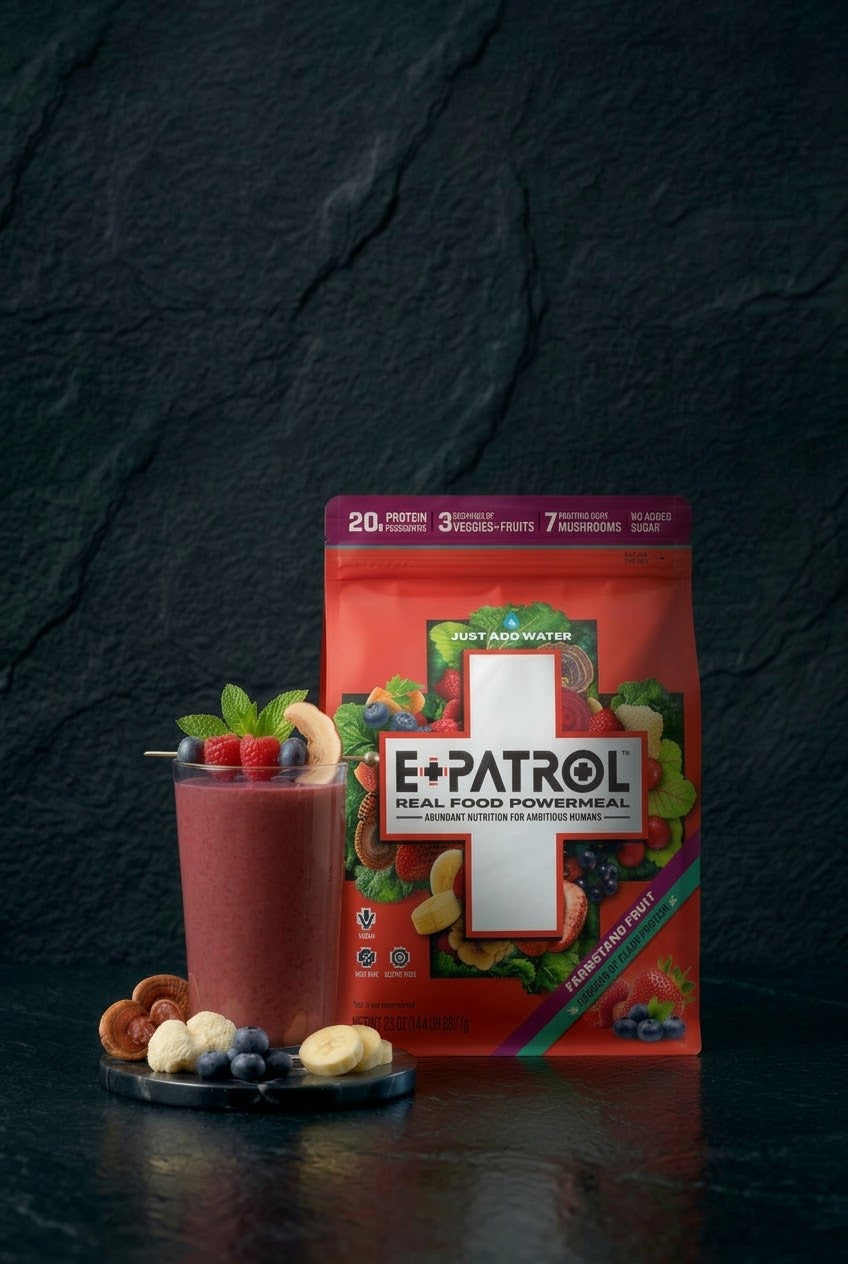 E+PATROL Farmstand Fruit smoothie mix pouch next to a glass of berry smoothie on a dark stone surface